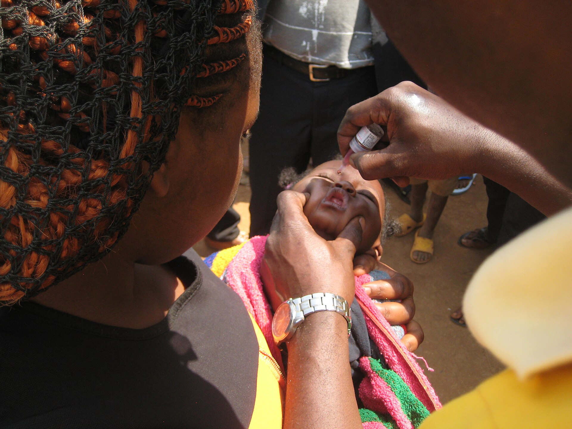 A young child receives a dose of oral polio vaccine.