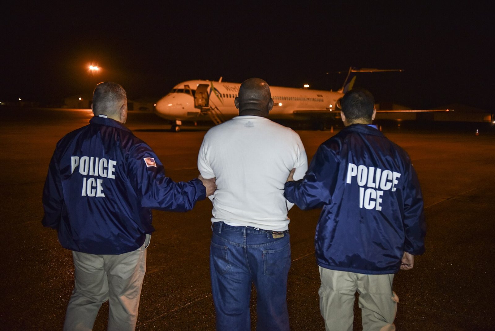 US immigration officers escort a man to a deportation charter flight.